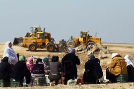 epa Bedouin women look at a bulldozer loading remains of houses on a truck after the Israeli military destroyed their houses in the Negev Desert