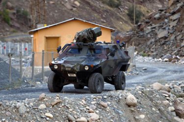 Turkish military armoured personnel carrier drives past a small patrol base high in the mountains of Cukurca near the Iraqi border in southeastern Turkey, where thousands of Turkish troops have launched a ground and air offensive against PKK fighters, October 21, 2011