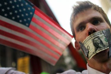 f_A protester wears a dollar bill over his mouth at the start of a march by demonstrators opposed to corporate profits on Wall Street on September 30, 2011 New York City