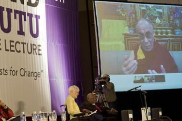 Nobel Prize Laureate Archbishop Desmond Tutu (C) listens to the Dalai Lama, speaking over a live video-link from Dharamsala, in India, during the International Peace Lecture, at the University of the Western Cape, on October 8, 2011 in Cape Town