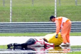 f_Race marshalls attend to Honda rider Marco Simoncelli (L) of Italy following a fatal crash four minutes after the start of the Malaysian MotoGP race in Sepang on October 23, 2011