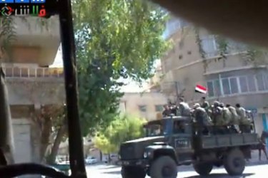 epa02867539 A grab made on 15 August 2011 from a handout video made available by Shaam News Network on its youtube channel, shows a soldier carrier passing at a steert in Al-Jesrain town, Syria.