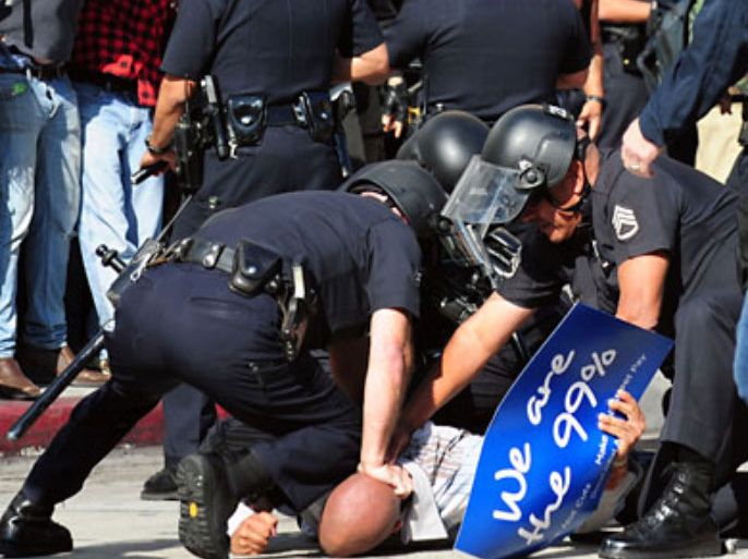 f_Police manhandle a protester to the ground as people watch in downtown Los Angeles, California on November 17, 2011 where over 20 anti-Wall Street protesters were arrested