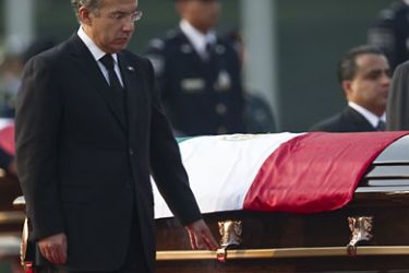 Mexican President Felipe Calderon stands next to the coffin of to his late Interior Minister Francisco Blake Mora, during a tribute ceremony in Mexico City, on November 12, 2011