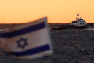 An Israeli flag flutters in the wind as a tug boat manoeuvres just outside the port of Ashdod November 4, 2011. The Israeli navy on Friday boarded two boats carrying pro-Palestinian activists towards the Gaza Strip in a fresh challenge to Israel's blockade of the Islamist-controlled territory.