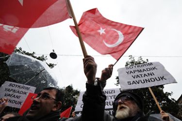 People wave Turkish flags and hold banners during a rally in front of the French Consulate in Istanbul on December 22, 2011,