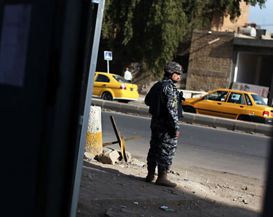 جندي عراقي يقف بجانب نقطة تفتيش في شارع يؤدي إلى ساحة كهرمانة في بغداد (رويترز)