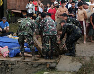 عناصر من الجيش الفلبيني ينتشلون جثة أحد القتلى قضى في الفيضانات (الفرنسية)