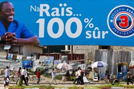 epa03015363 Pedestrians walk in front of a billboard for incumbent President Joseph Kabila reading '100% Safe' in central Kinshasa, the Democratic Republic of Congo,