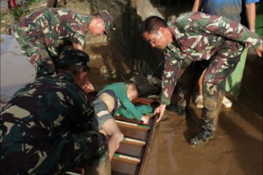 Philippine military personnel prepare to carry the dead body of a boy victim of the floods caused by tropical storm Washi at a village in Iligan City, on the southern island of Mindanao on December 17, 2011