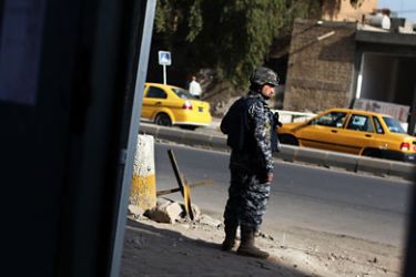 An Iraqi police officer stands guard along a street near Kahramana Square in Baghdad December 10, 2011. REUTERS