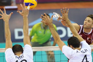 Qatar's Ziad Benlouaer (red) spikes the ball over Ahmed Abdelhay (R) and Mohammed Ketat (L) during their men's gold medal volleyball match at the 2011 Arab Games in the Qatari capital Doha on December 22, 2011. AFP
