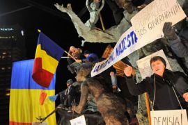 A woman shouts as she holds a sign reading "QUIT!" referring to Romanian president Traian Basescu and prime minister Emil Boc, as protesters shouts anti-presidential slogans during a protest rally in Bucharest, on January 22, 2012.