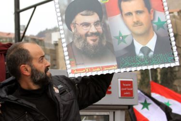 A Syrian man holds a picture of Syrian President Bashar al-Assad (R) and Lebanon's Hezbollah chief Hassan Nasrallah during a pro-regime rally in Damascus on January 11, 2012. Assad made a rare public appearance at the rally, vowing to defeat a "conspiracy" against Syria a day after he blamed foreign interests for stoking months of deadly violence.