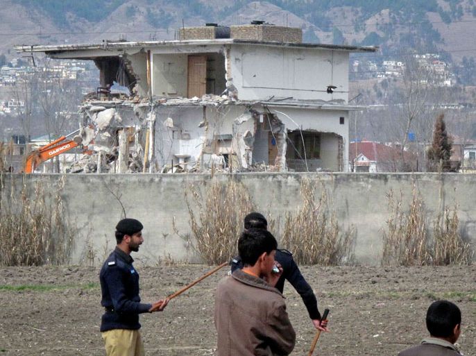 Policemen and residents stand near while demolition work is carried out on the building where al Qaeda leader Osama bin Laden was killed by U.S. special forces last May, in Abbottabad February 26, 2012. Pakistani forces began demolishing the house where al Qaeda leader Osama bin Laden was killed by U.S. special forces last May, in an unexplained move carried out in the dark of night. REUTERS/Sultan Dogar (PAKISTAN - Tags: POLITICS CRIME LAW CONFLICT)