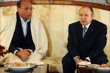 Tunisian President Moncef Marzouki (L) chats with Algeria's President Abdelaziz Bouteflika (R) upon arrival at the airport in Algiers, as part of his first official visit and the final stage