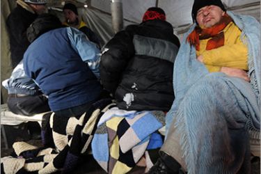 Homeless people warm themselves in one of newly opened tent shelters in the center of the western Ukrainian city of Lviv on February 3, 2012. A week of ferociously cold temperatures in Ukraine has now claimed 101 lives, the Ukrainian emergencies ministry said in a statement Friday. AFP PHOTO/ YURIY DYACHYSHYN