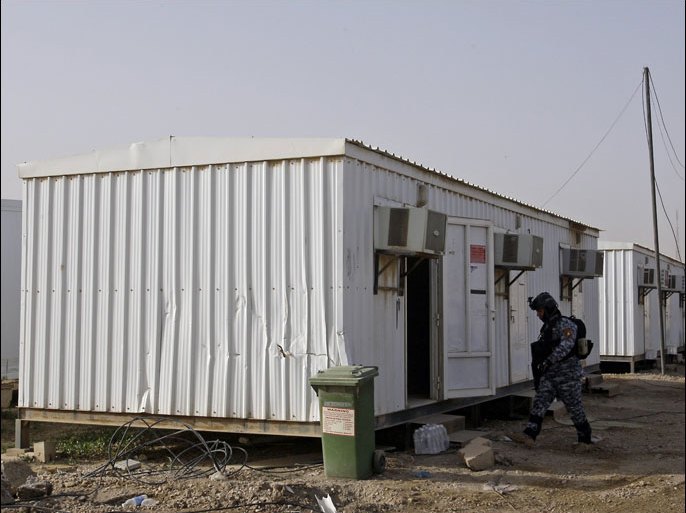 afp : An Iraqi soldier inspects prefabricated houses at the former US military base Camp Liberty, which will be the new temporary home of exiled Iranian opposition members, near Baghdad's international airport on February 17, 2012. The first group of Iranian exiles will leave Camp Ashraf in Diyala province and move to the base ahead of a resettlement outside Iraq under a plan agreed with the United Nations. AFP PHOTO/ALI AL-SAADI