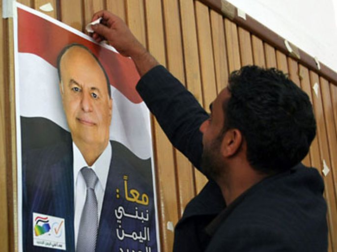 supporter of Yemen's Vice President Abdrabuh Mansur Hadi, who is the country's acting leader, tapes his poster onto the wall during the inauguration ceremony for his presidential election campaign, in Sanaa on February 7, 2012. Yemen has begun a publicity campaign to get