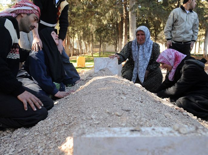 Syrians mourn over the fresh grave of a relative at a cemetery following a funeral for victims killed in violence in Idlib in northwestern Syria on February 25, 2012.