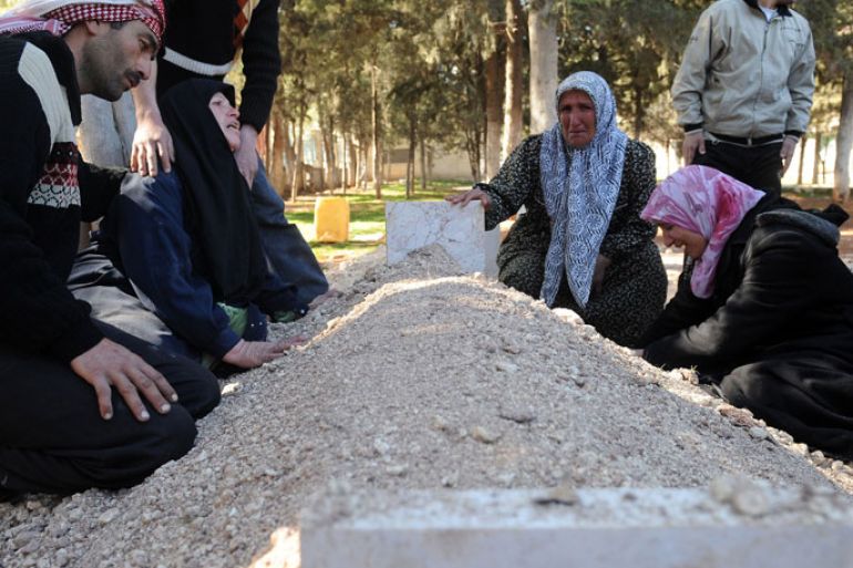 Syrians mourn over the fresh grave of a relative at a cemetery following a funeral for victims killed in violence in Idlib in northwestern Syria on February 25, 2012.