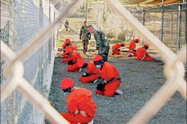 Detainees sit in a holding area during their processing into the temporary detention facility, as they are watched by military police, at Camp X-Ray inside Naval Base Guantanamo Bay in this January 11, 2002 file photograph. Al Qaeda leader Osama bin Laden was killed in a firefight with U.S. forces in Pakistan on May 1, 2011, ending a nearly 10-year worldwide hunt for the mastermind of the Sept. 11 attacks. "Justice has been done," U.S. President Barack Obama declared in a hastily called, late-night White House speech announcing the death of the elusive head of the militant Islamic group behind a series of deadly bombings across the world. REUTERS/U.S. Department of Defense/Petty Officer 1st class Shane T. McCoy/Handout/Files (CUBA - Tags: CIVIL UNREST POLITICS) FOR EDITORIAL USE ONLY. NOT FOR SALE FOR MARKETING OR ADVERTISING CAMPAIGNS