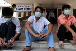 Men wearing masks sit on the doorsteps of the National Institute for Tropical diseases, a main venue for swine flu patients in Hanoi on August 5, 2009