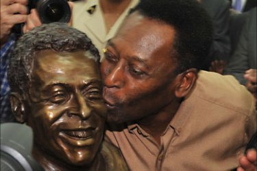 Brazilian football legend Pele kisses a just inaugurated statue of himself at the stade de l'Amitie in Libreville on February 9, 2012,