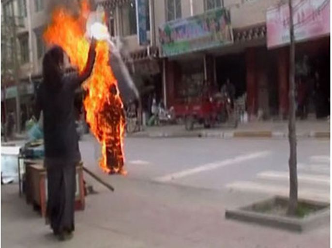 R_A woman throws a white scarf over Tibetan Buddhist nun Palden Choetso as she burns on the street in Daofu, or Tawu in Tibetan, in this still image taken from video shot