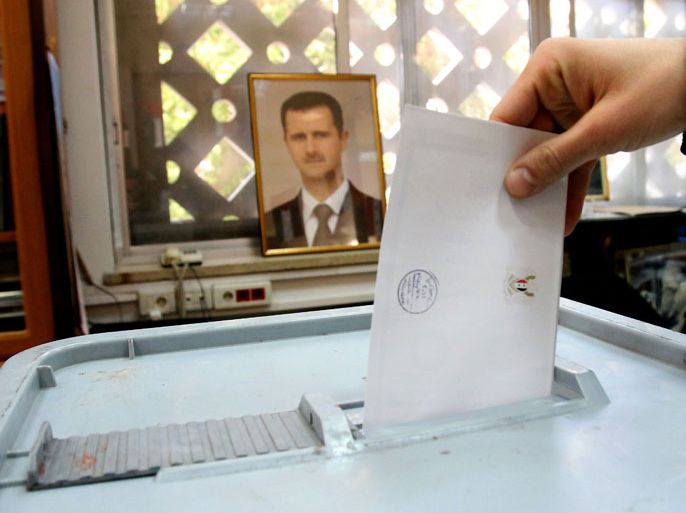 A Syrian man casts his ballot in front of a picture of Syrian President Bashar al-Assad at a polling station in Damascus on February 26, 2012 as Syrians were called to the polls to vote on a new constitution in the face of opposition calls for a boycott and in the thick of deadly violence that Washington said made the exercise "laughable." AFP PHOTO/ANWAR AMRO