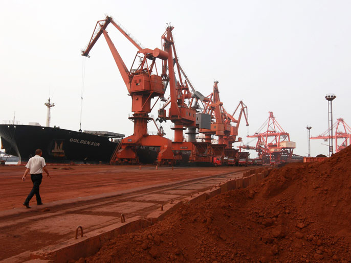In a file photo taken on September 5, 2010, a man walks by as bulldozers scoop soil containing various rare earth to be loaded on to a ship at a port in Lianyungang, east China's Jiangsu province, for export to Japan