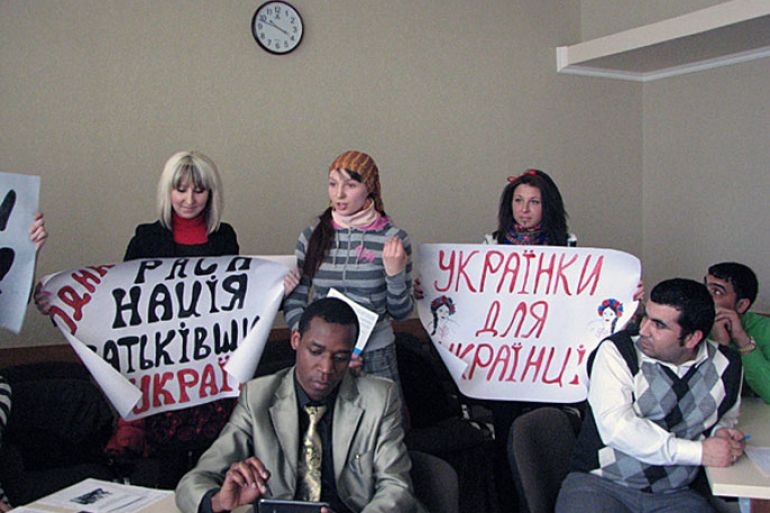 فتيات عنصريات يحملن شعارات تطالب بتحرير أوكرانيا من الأجانب خلال الندوة