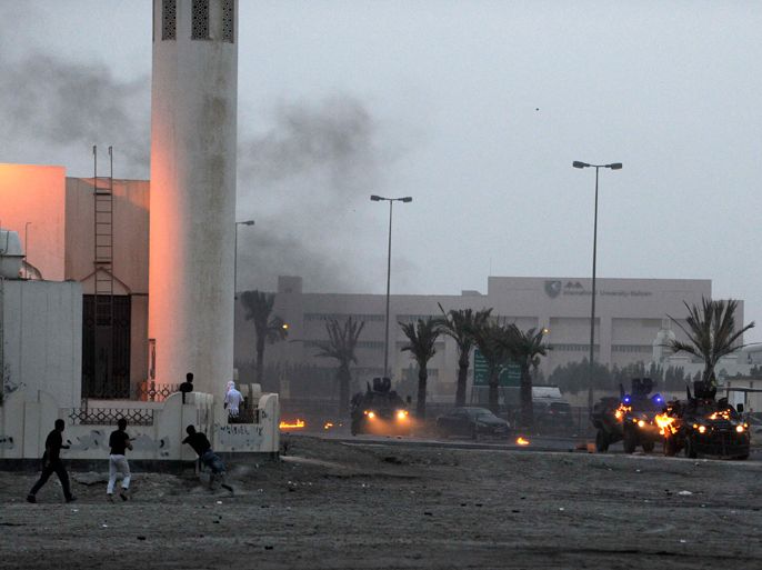 An anti-government protester throw Molotov cocktails at riot-police armoured personnel carriers during a protest against the murder of Ahmed Ismael Abdulsamad in Salmabad village south of Manama, March 31, 2012. Abdulsamad died early Friday from a single gunshot wound to the thigh fired from a moving car, Ministry of Interior statement said.