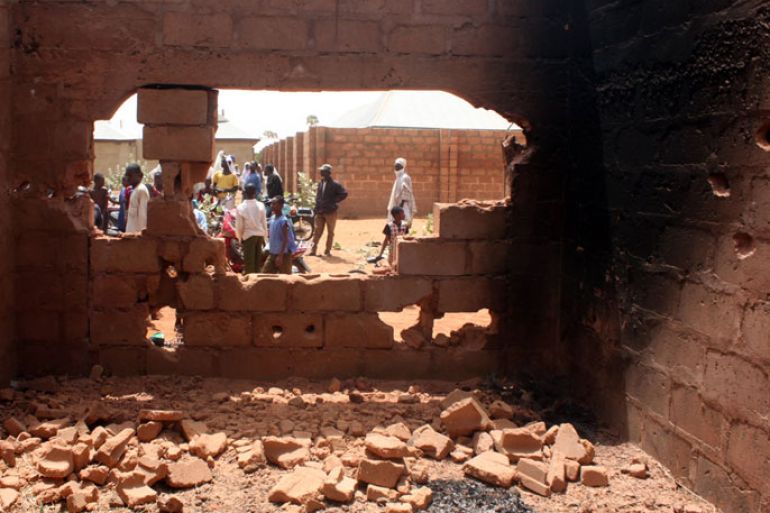 ARE003 - Sokoto, -, NIGERIA : People stand outside an uncompleted building where tyres were burnt while kidnappers attempted to escape during the failed rescue operation of a pair of British and Italian hostages by Nigerian special forces at Mabera Area in Sokoto on March 9, 2012. Italy on Friday condemned as "inexplicable" Britain's failure to warn it ahead of time of an operation to rescue a pair of British and Italian hostages in Nigeria that resulted in their deaths. "The behaviour of the British government, which did not inform or consult with Italy on the operation that it was planning, really is inexplicable," President Giorgio Napolitano told reporters a day after the assault. AFP PHOTO / EMMANUEL AREWA