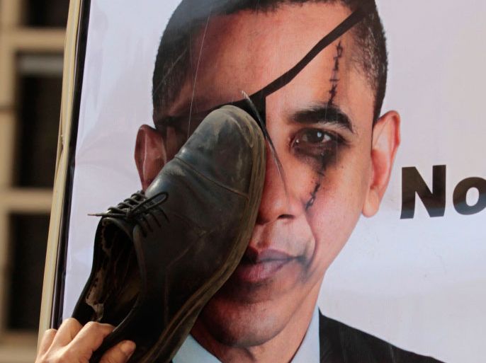An Egyptian protester hits a portrait of U.S. President Barack Obama with a shoe in front of the U.S. embassy in Cairo, March 9, 2012, condemning the decision of the Ruling Supreme Council of the Armed Forces (SCAF) to release American activists who were involved in what is known as NGOs foreign fund case. REUTERS/Mohamed Abd El Ghany (EGYPT - Tags: POLITICS CIVIL UNREST)