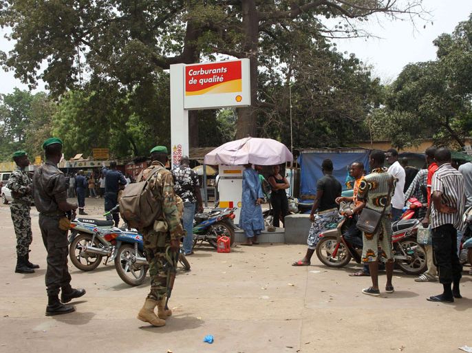 Putschist soldiers (L) watch and protect people queuing at a gas station on March 24, 2012 in Bamako, three days after Malian President Amadou Toumani Toure was forced to flee his palace during an overnight coup. In the capital Bamako, few people ventured outside and there were complaints of cash machines running low on money and petrol shortages as trucks backed up at the borders which have been closed since the coup. Mali's putschists, frozen out by the international community, sought to assert their tenuous hold on power Saturday amid rumours of a loyalist backlash against their two-day old junta. AFP PHOTO/ HABIBOU KOUYATE
