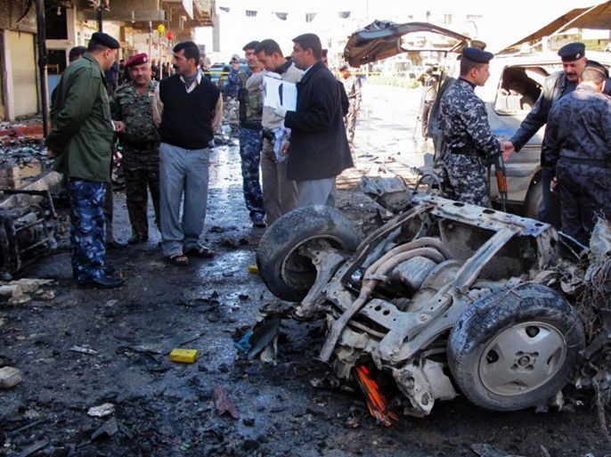 Iraqi policemen inspect the site of a car bomb in the central town of Hilla, south of the capital, on March 20, 2012, which killed two people and wounded 31 others