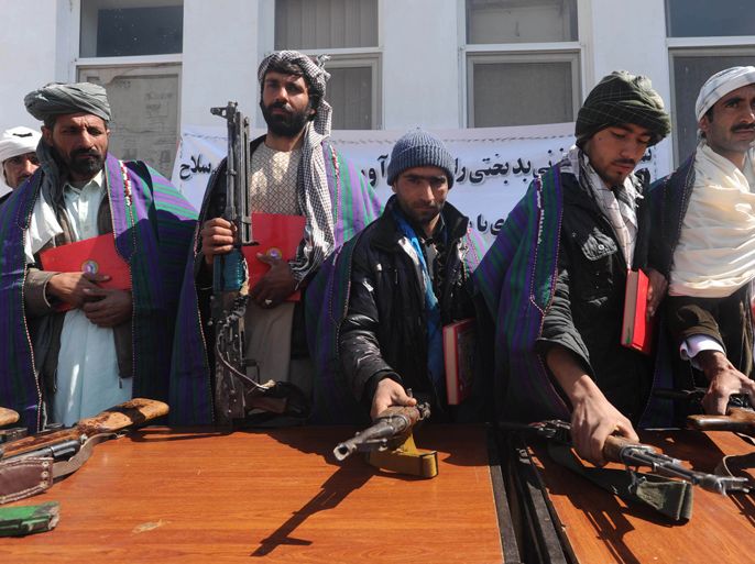Taliban fighters stand with their weapons as they hold Korans after joining Afghan government forces during a ceremony in Herat province on March 7, 2012. Taliban insurgents claimed responsibility for a suicide attack that killed at least two civilians at a US military base near the Afghan capital Kabul on March 5, saying it was revenge for the burning of Korans there. AFP