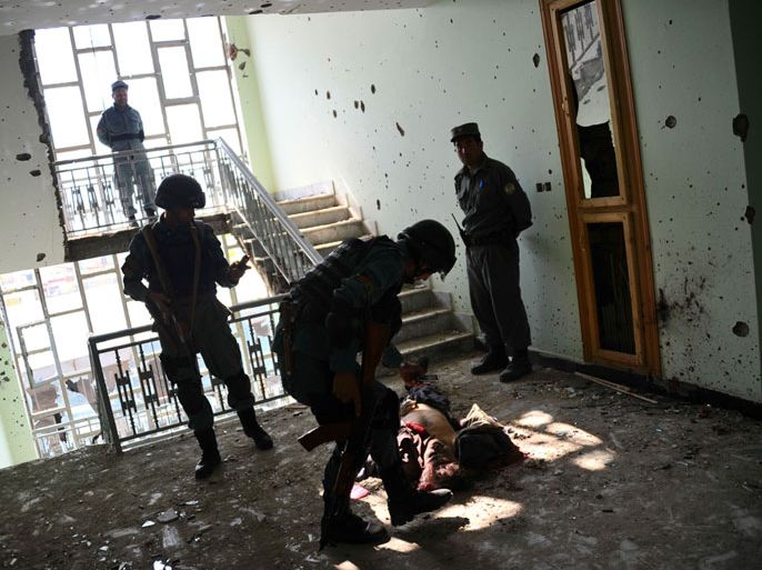 Afghan police officers use mobile phones to photograph the dead body of an insurgent on the floor of a room with bullet riddled walls in Kabul on April 16, 2012. All 15 militants involved in a wave of attacks in Afghanistan's capital were killed, authorities said on April 16. The heavily armed rebels stormed several areas of Kabul on April 15, targeting government buildings, embassies and military bases in an assault that ended 17 hours later, on April 16. AFP PHOTO/Bay ISMOYO