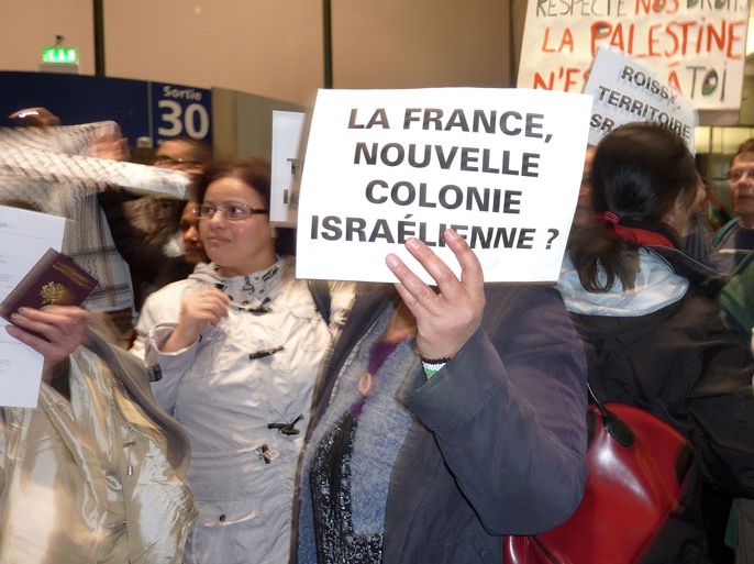 Roissy-en-France, Val-d'Oise, FRANCE : Dozens of pro-palestinian activists taking part in the "Welcome to Palestine" campaign protest at the Roissy International airport on April 15, 2012 in Roissy-en-France, northern Paris suburb, after being denied to board planes to Israel. Israel warned foreign airlines they would be forced to foot the bill for the activists' immediate return and at least four European carriers cancelled tickets for a number of passengers heading to Tel Aviv. The campaign's organisers say they want to publicise Israel's control of movement into and out of the occupied Palestinian territories and to demonstrate solidarity with the Palestinian people. Board reads : "France, new Israeli colony?". AFP PHOTO / VALENTIN BONTEMPS