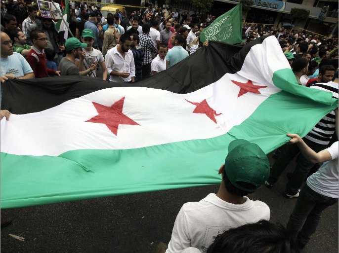 Supporters loyal to the Future movement and Jamaa Islamiyyah hold up a large Syrian flag as they demonstrate against the Syrian regime of Bashar al-Assad following Friday prayer in Beirut's Tariq al-Jadideh, Sunni Muslim neighborhood on April 20, 2012. AFP PHOTO/JOSEPH EID