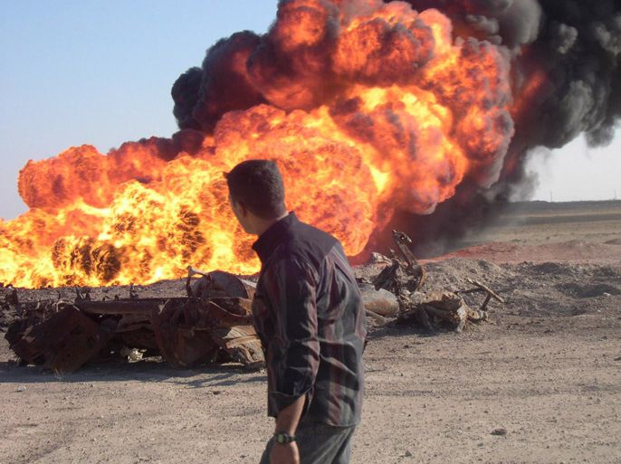epa00602957 An Iraqi man looking at a burning oil pipeline that was brought to an explosion by unidentified insurgents in Samarra, north of Baghdad, on Monday, 26