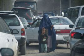 EIS02 - Kabul, -, AFGHANISTAN : An Afghan woman with her son begs in the midst of a traffic jam in Kabul on April 26, 2012. The position of women in Afghanistan has improved dramatically since the fall of the Taliban, with the number of girls in education soaring. AFP PHOTO/ JOHANNES EISELE