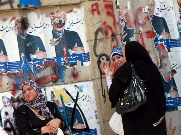 Egyptian women chat next to a wall covered in torn campaign posters of presidential candidate and former prime minister Ahmed Shafiq in Cairo on April 26, 2012. Egypt's electoral commission went back on a decision to bar Shafiq, ousted leader Hosni Mubarak's last prime minister, from running in the May 23 presidential election. AFP PHOTO/KHALED DESOUKI