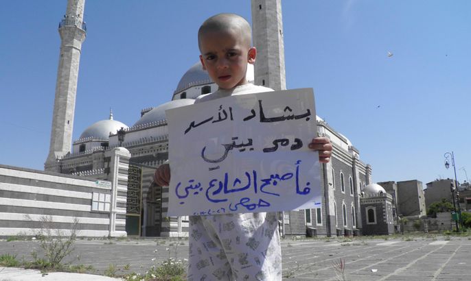A boy holds a sign that reads, "Bashar Al Assad destroyed my home, the street has become my home", in front of Khaled Bin Al Waleed mosque in the centre of Homs April 26, 2012. Picture taken April 26. REUTERS
