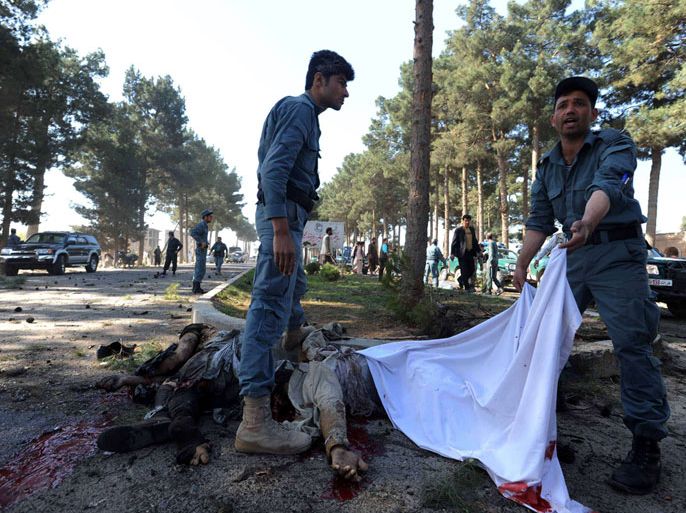 Afghan policemen cover dead bodies at the site of a suicide bomb attack in Herat province on April 10, 2012. At least nine people were killed when two suicide bombers rammed their vehicle into a local government compound near Afghanistan's western city of Herat on on April 10, police and witnesses said. Provincial police chief Sayed Agha Saqeb told reporters that the bombers were being pursued by police when they detonated the vehicle at the entrance to the Guzara district compound along the road from the airport to the city. "Nine people are dead. The car was under our surveillance. It was ordered twice to stop but they didn't stop," said the police chief. AFP PHOTO/Aref Karimi