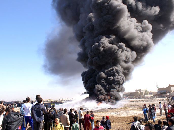 epa01594644 Iraqis stand near a burning oil pipeline in central Basra, southern
