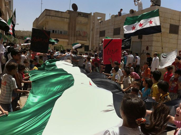 BEI660 - Aleppo, -, SYRIA : A handout image released by the Syrian opposition's Shaam News Network on May 23, 2012 shows Syrian protesters carrying a huge pre-Baath national flag, which has been adopted by the opposition movement, during an anti-regime demonstration in Aleppo. A UN panel said on May 24 that government forces are to blame for most rights abuses in the latest unrest sweeping Syria as a watchdog reported an 11th straight day of shelling of a rebel bastion