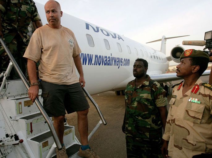 One of the four foreigners captured whilst investigating debris from recent fighting between Sudan and South Sudan in the Heglig oilfield area on April 28, 2012, is escorted off an airplane by Sudanese soldiers in Khartoum