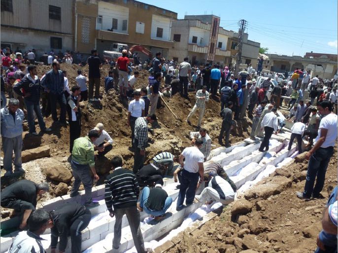 A handout picture released by the Syrian opposition's Shaam News Network shows people watching the mass burial on May 26, 2012 of more than 100 victims killed in the central Syrian city of Houla in a massacre condemned by world leaders and described on May 28 by visiting UN-Arab League envoy Kofi Annan as "an appalling moment with profound consequences." While Syria's opposition renewed its call to the international community to help Syrians defend themselves, Damascus' UN envoy Bashar Jaafari said accusations of government responsibility for the Houla attack were part of a "tsunami of lies." AFP PHOTO / HO / SHAAM NEWS NETWORK